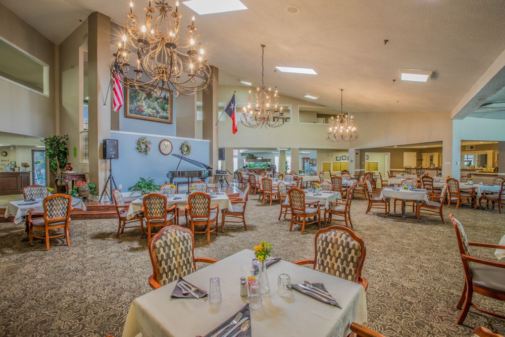 A spacious dining area with chandeliers, elegantly set tables, and a formal atmosphere.