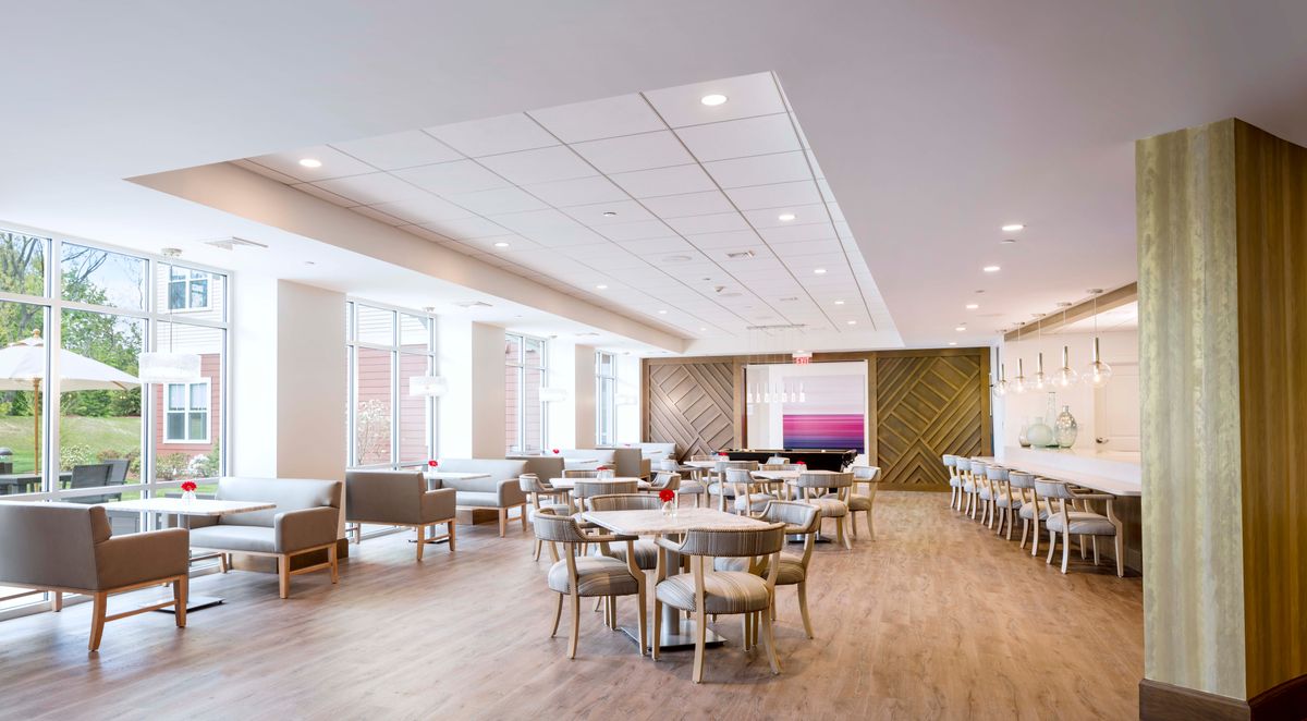 A modern lounge with tables and chairs, featuring bright lighting and a spacious design.