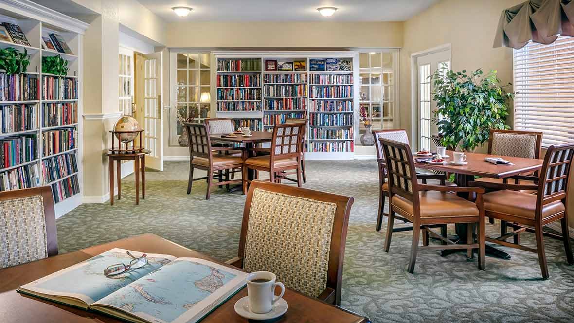 A cozy reading area with bookshelves, tables, and chairs.