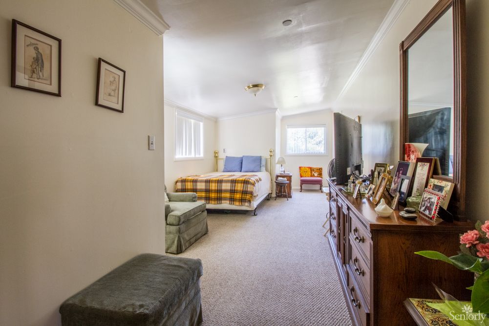 A cozy bedroom with a comfortable bed, surrounded by various pieces of furniture and decor.