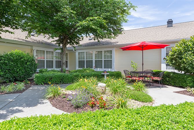 A well-maintained garden patio with outdoor seating and a red umbrella.