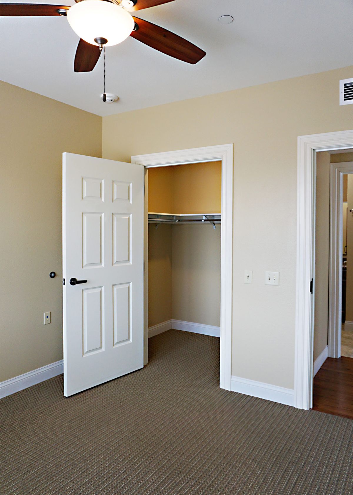 An empty room with beige walls and an open closet.
