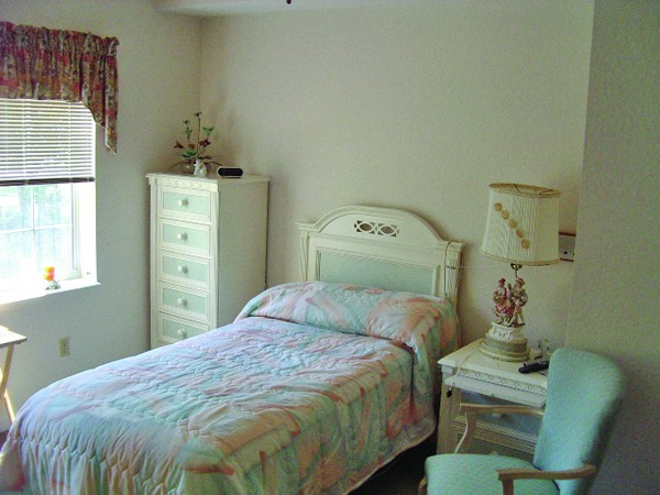 A cozy bedroom with a single bed, dresser, and matching furniture.