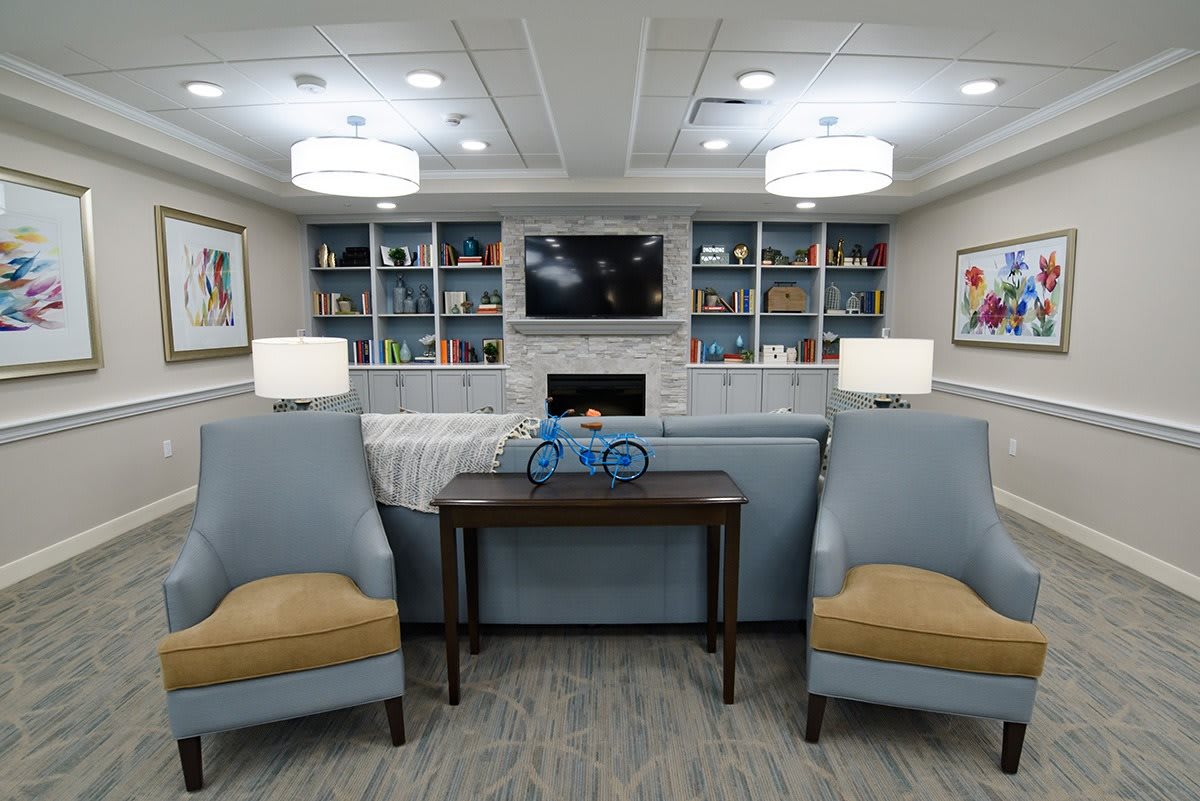 A cozy living room with comfortable seating, bookshelves, and ambient lighting.