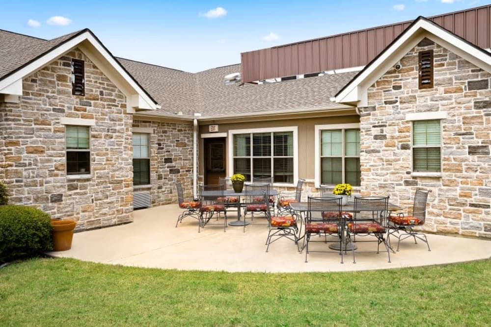 A cozy backyard patio with outdoor seating set against a brick house.