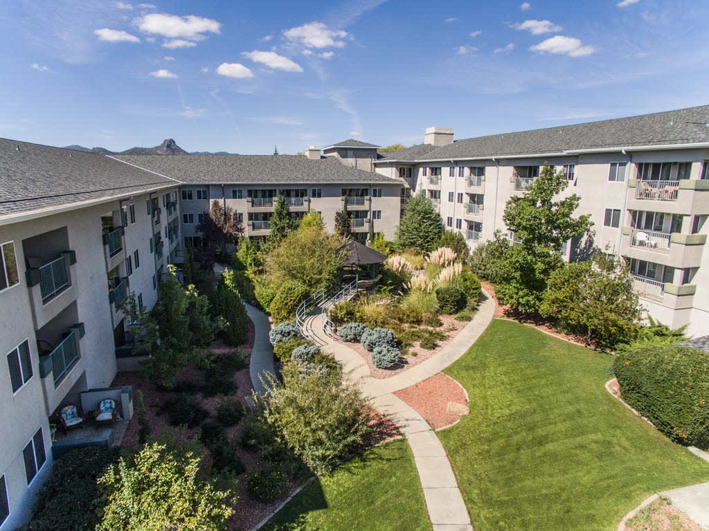 Aerial view of a well-maintained apartment complex courtyard with lush gardens and winding pathways.