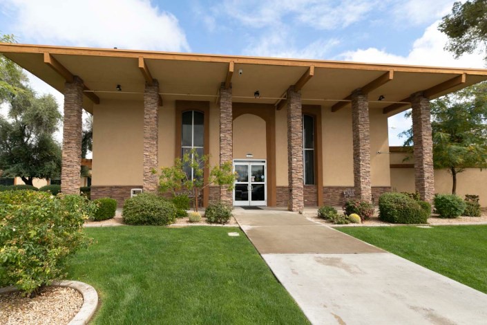 A modern building with large columns and well-maintained landscaping under a partly cloudy sky.