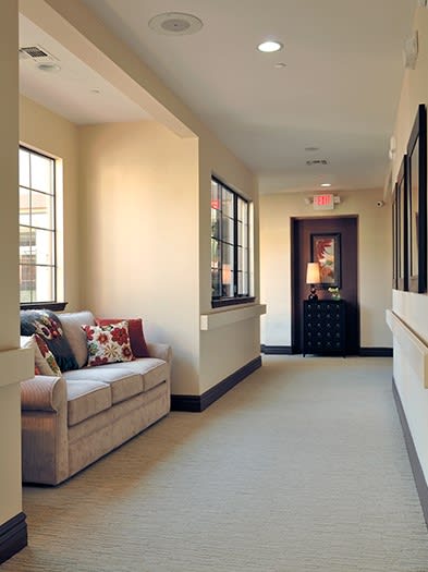 A cozy hallway with a couch by the windows, featuring soft lighting and decorative pillows.