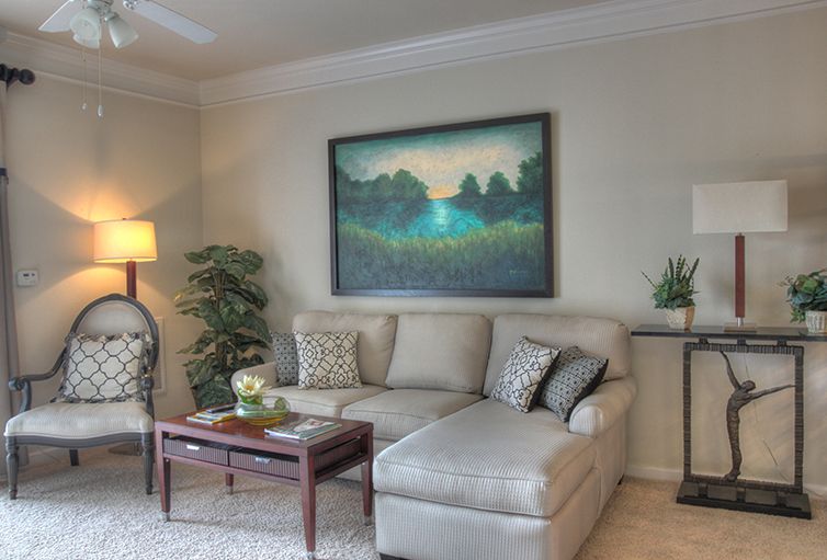 A cozy living room with a beige sofa, decorative pillows, and a large painting above.