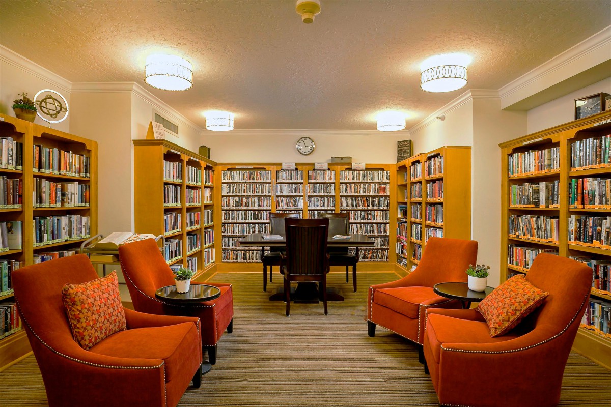A cozy reading area in a library with bookshelves, comfortable chairs, and a table.