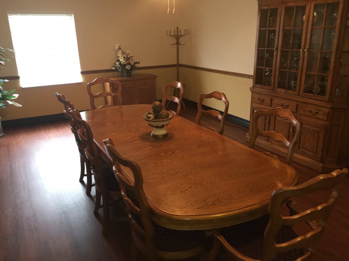 A neatly arranged dining room with a large wooden table and matching chairs.