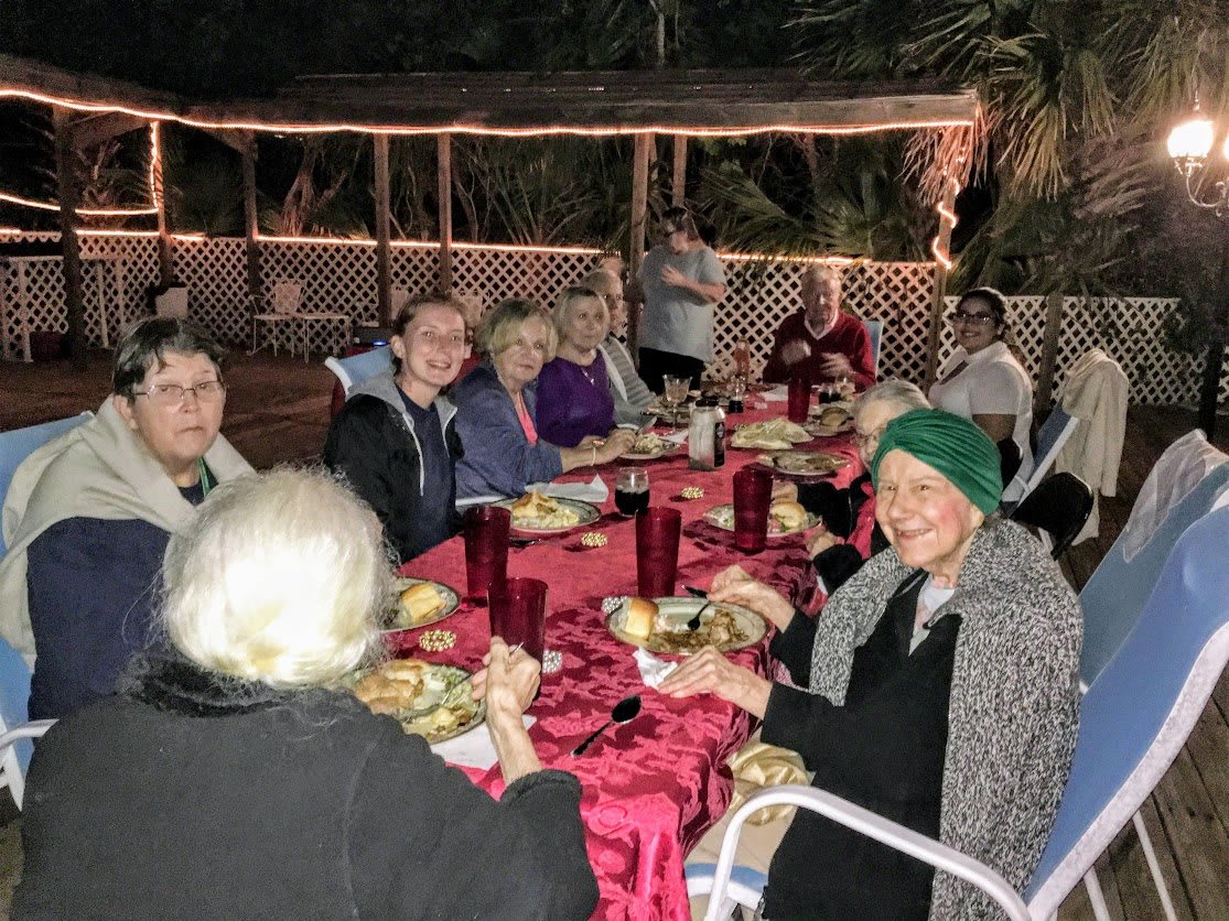 A group of people enjoying an outdoor dinner gathering at night.