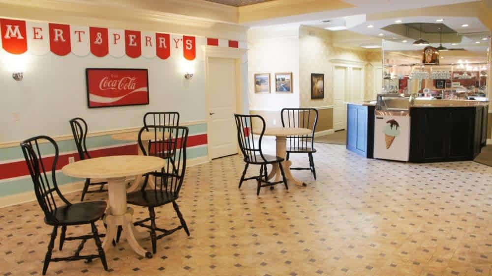 An empty vintage-style diner interior featuring tables and chairs, with classic Coca-Cola signage on the wall.