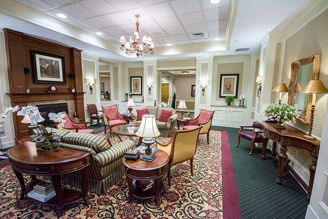 A traditional living room featuring elegant furniture, a chandelier, and a patterned carpet.