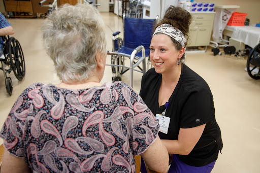 A nurse engaging and smiling with an elderly patient in a healthcare setting.