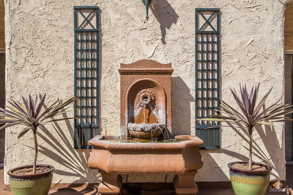 A decorative outdoor wall fountain in a garden setting.