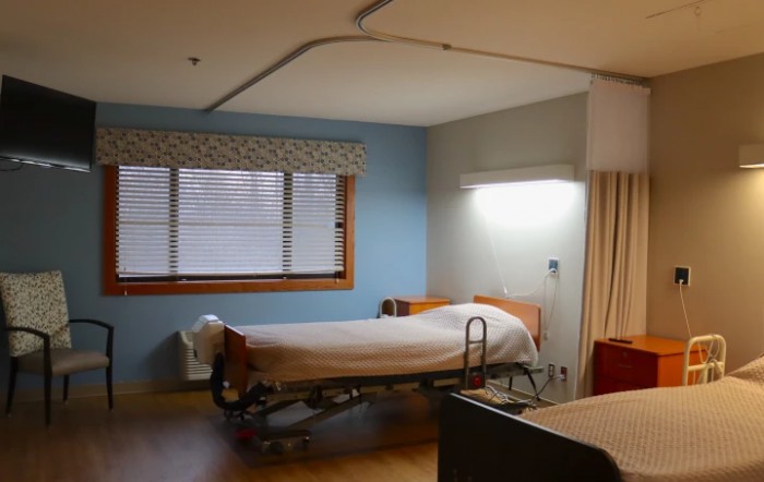 A clean and empty hospital room with a single bed and medical equipment.