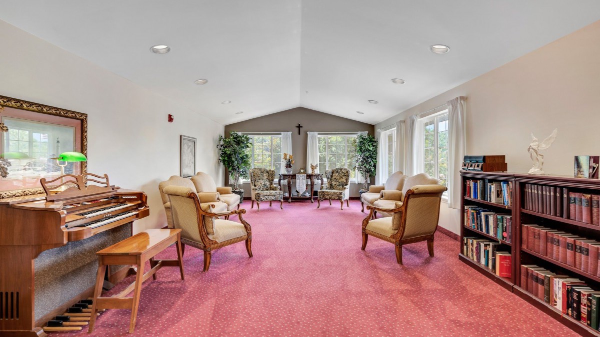 A cozy living room with armchairs arranged around a coffee table, featuring large windows and warm decor.