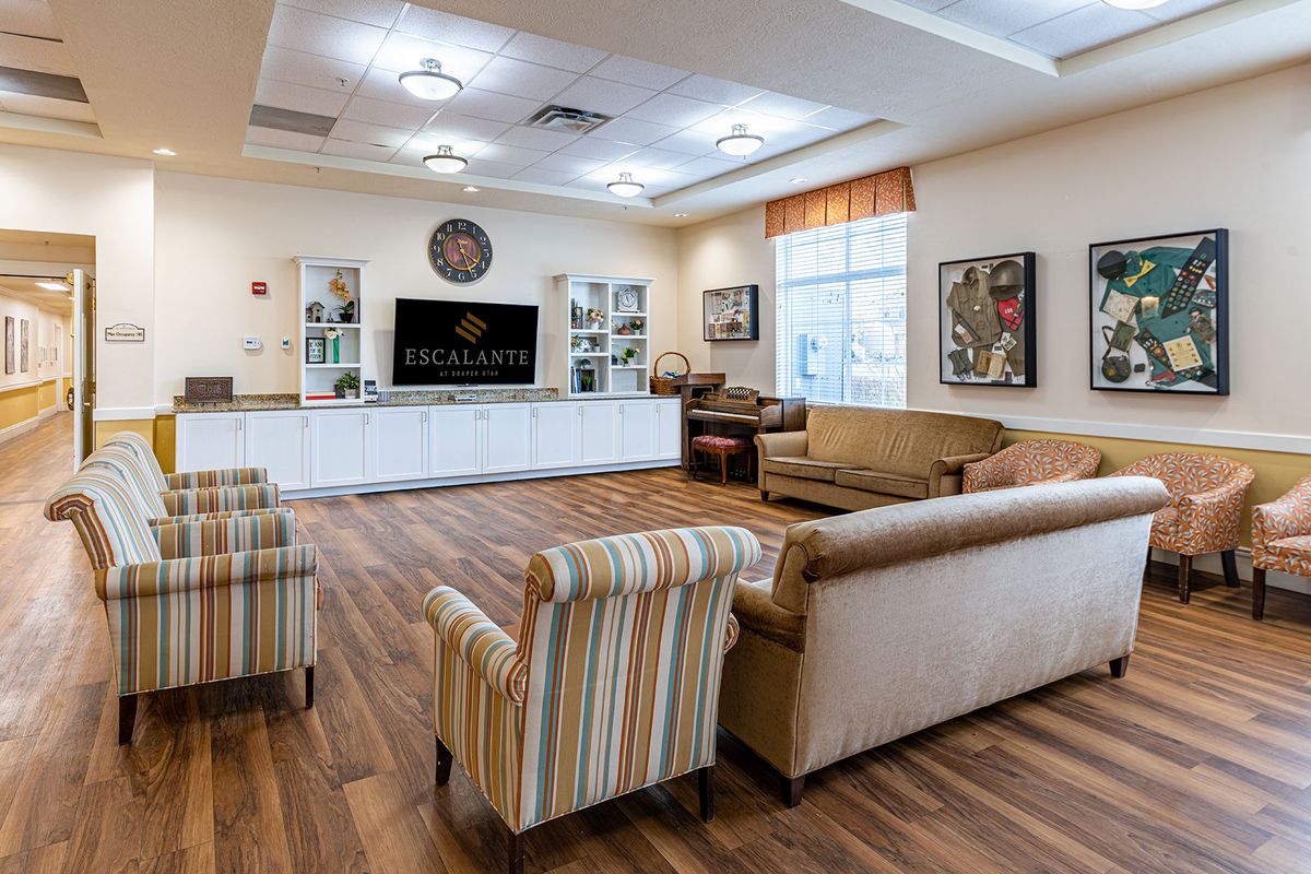 A cozy living room interior with sofas, stylish chairs, a large television, and warm wood flooring.