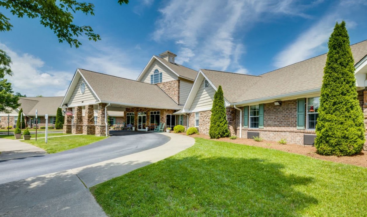 A charming residential building with a welcoming driveway and well-maintained lawn under a blue sky.