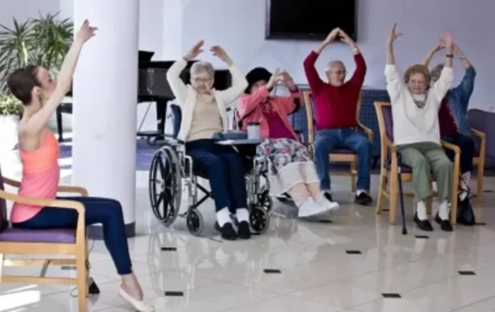 A group of elderly individuals participating in an exercise session indoors.