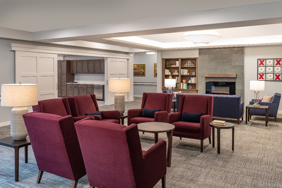 A cozy lounge area featuring red armchairs and a bookshelf.