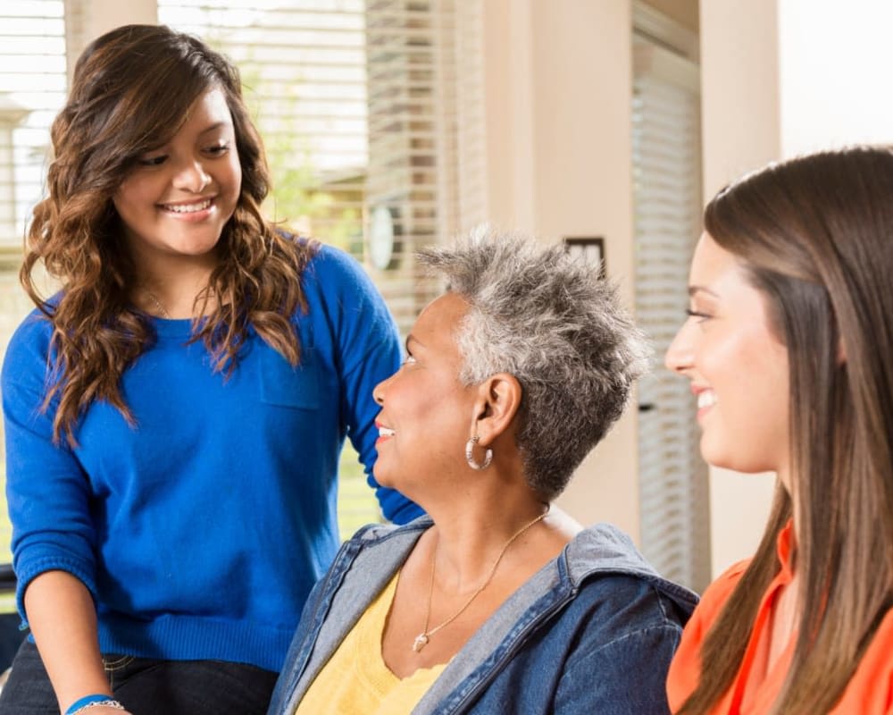 A group of three people engaging in a friendly conversation at home.