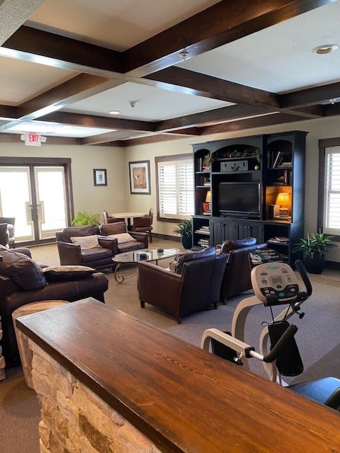 A cozy living room featuring comfortable seating, a TV setup, and an exercise bike.
