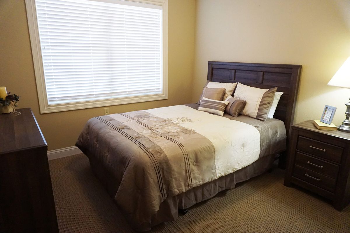 A cozy bedroom with a neatly made bed and neutral decor.