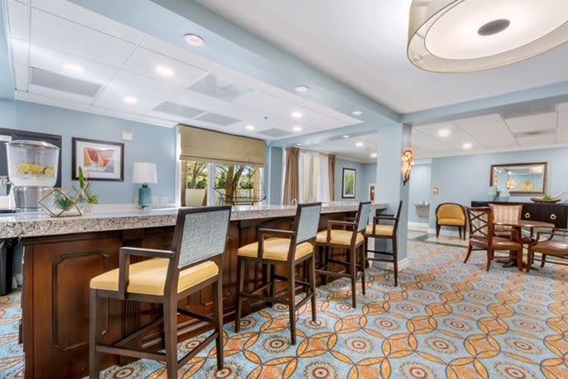 A stylish bar area with high seating, intricate carpet design, and modern lighting fixtures.