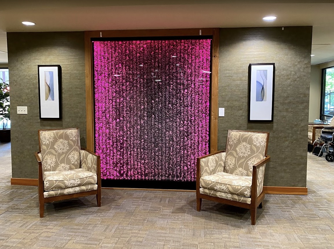 A modern lobby area with two patterned chairs and a colorful digital artwork on the wall.