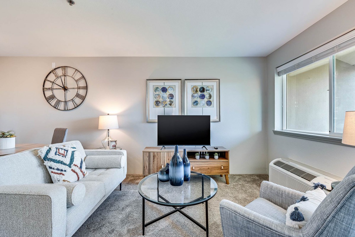 A modern living room with stylish decor, featuring a sofa, coffee table, and television.