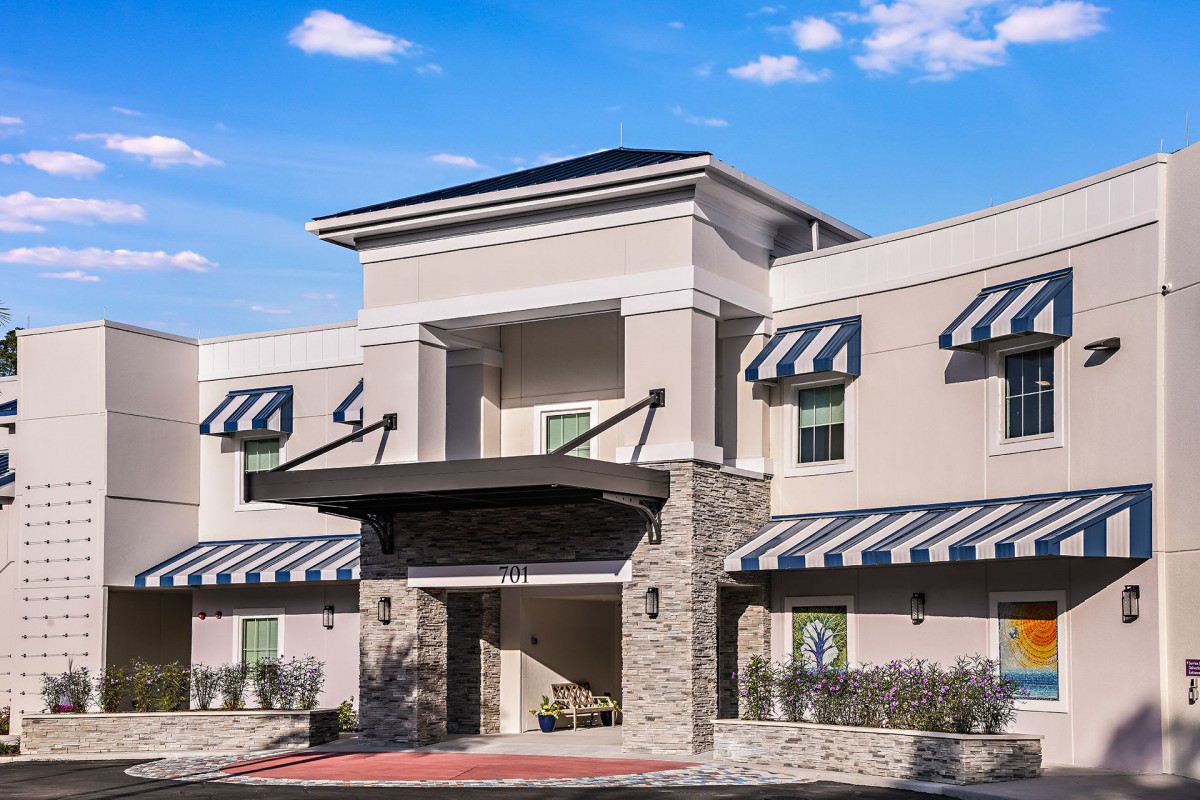Modern hotel entrance with striped awnings and stone facade.
