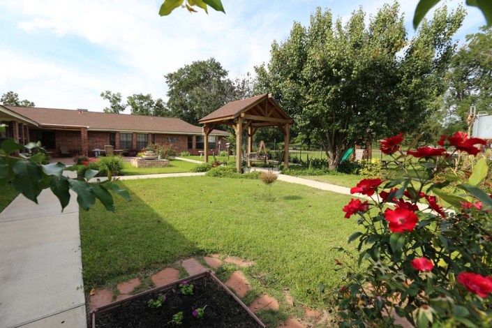 A well-maintained garden with a gazebo, vibrant flowers, and lush greenery.