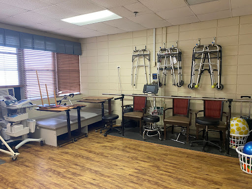 A spacious medical room equipped with various chairs and tables, designed for rehabilitation or therapy.