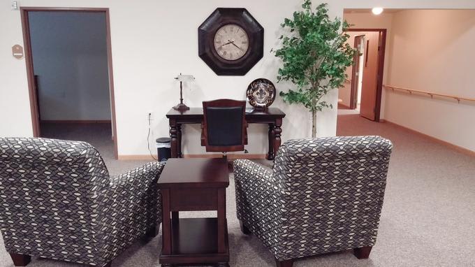 A cozy office setup featuring a desk, decorative clock, and patterned chairs.