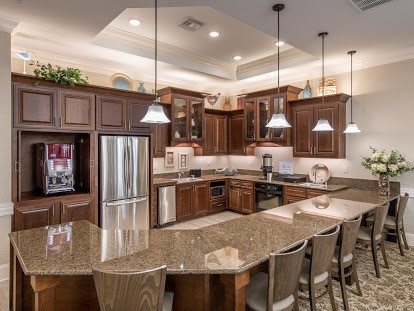 A modern kitchen with wooden cabinets, a curved countertop, and bar stools.