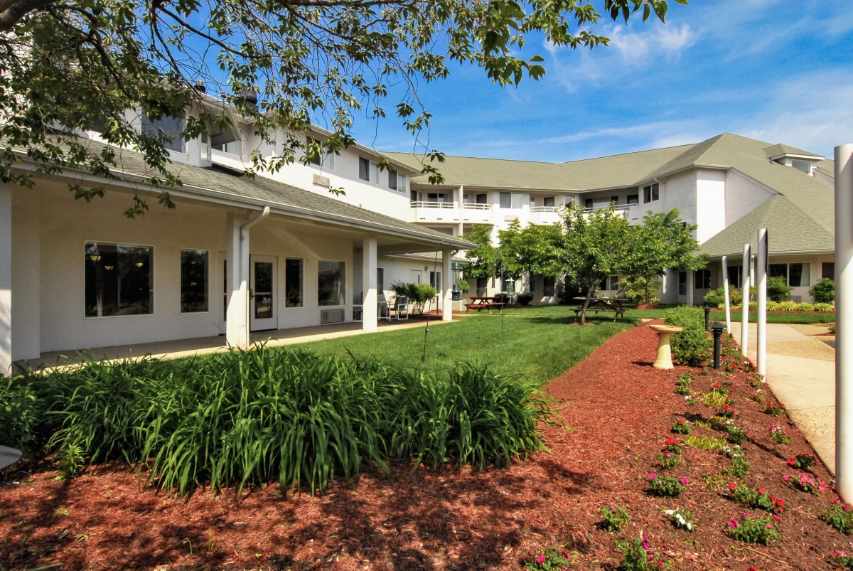 A well-maintained residential building with a landscaped garden and trees.