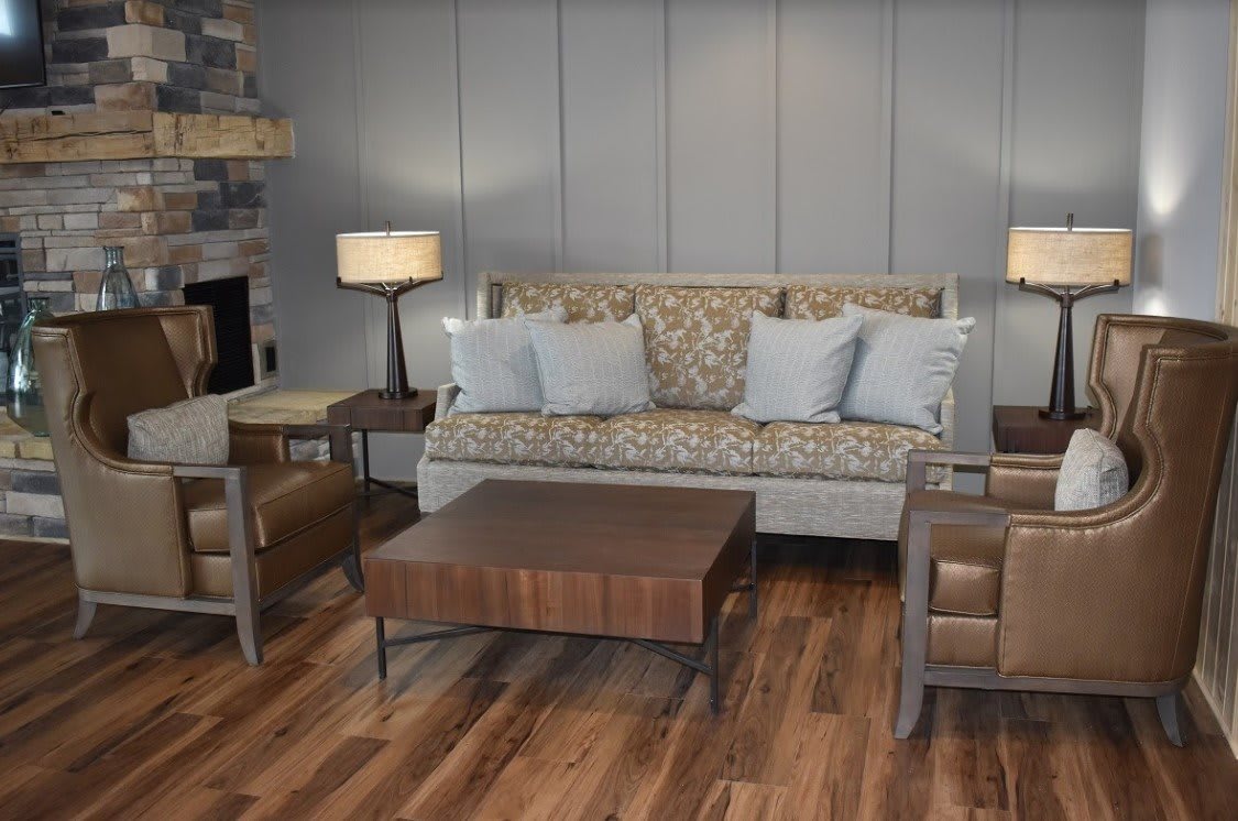 A cozy living room with a patterned sofa, armchairs, and a wooden coffee table on a wooden floor.