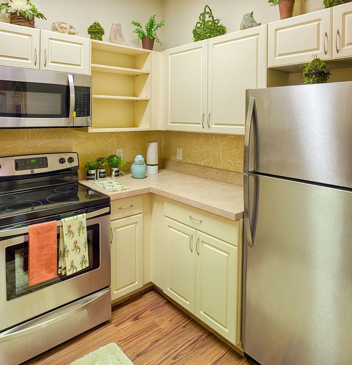 A modern kitchen featuring stainless steel appliances and cream-colored cabinets.