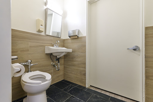 A clean and modern bathroom featuring a toilet, sink, mirror, and simple decor.