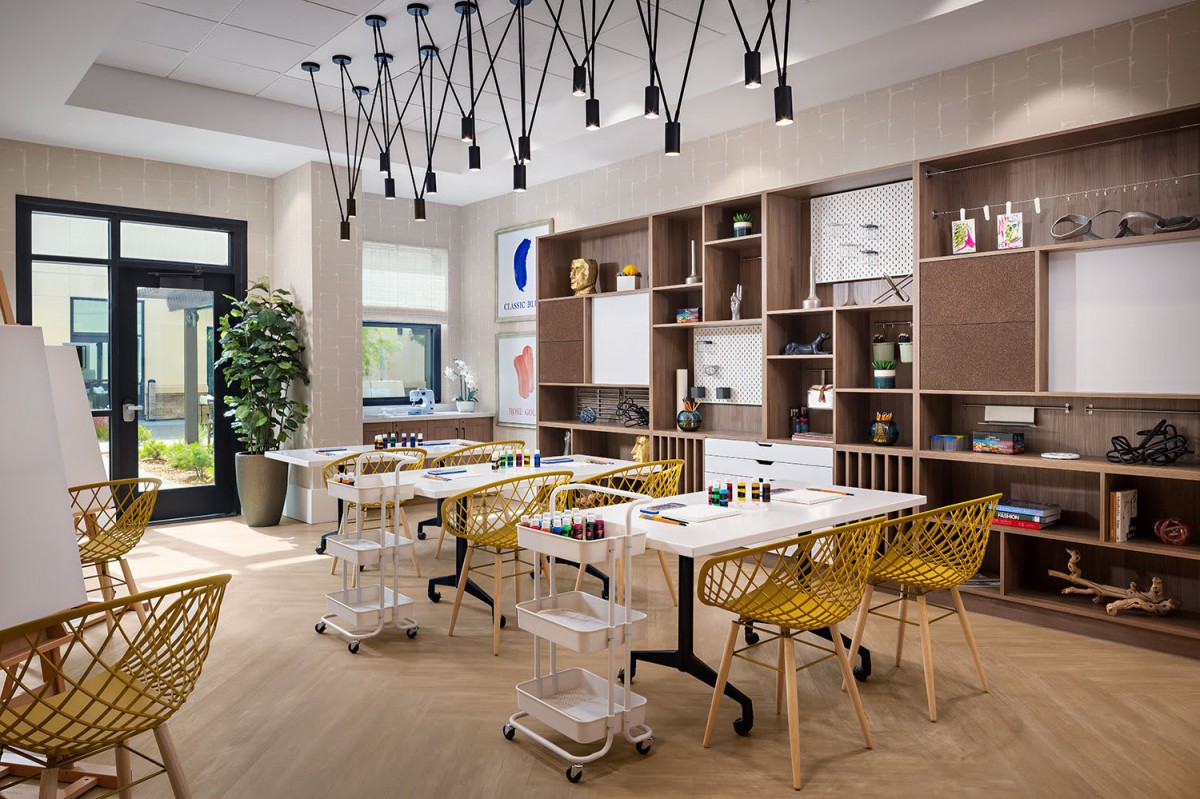 A modern dining room with yellow chairs, pendant lighting, and wooden flooring.