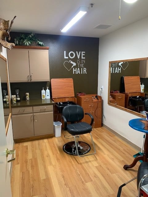 A cozy hair salon interior with a styling chair, large mirror, and hair care products.