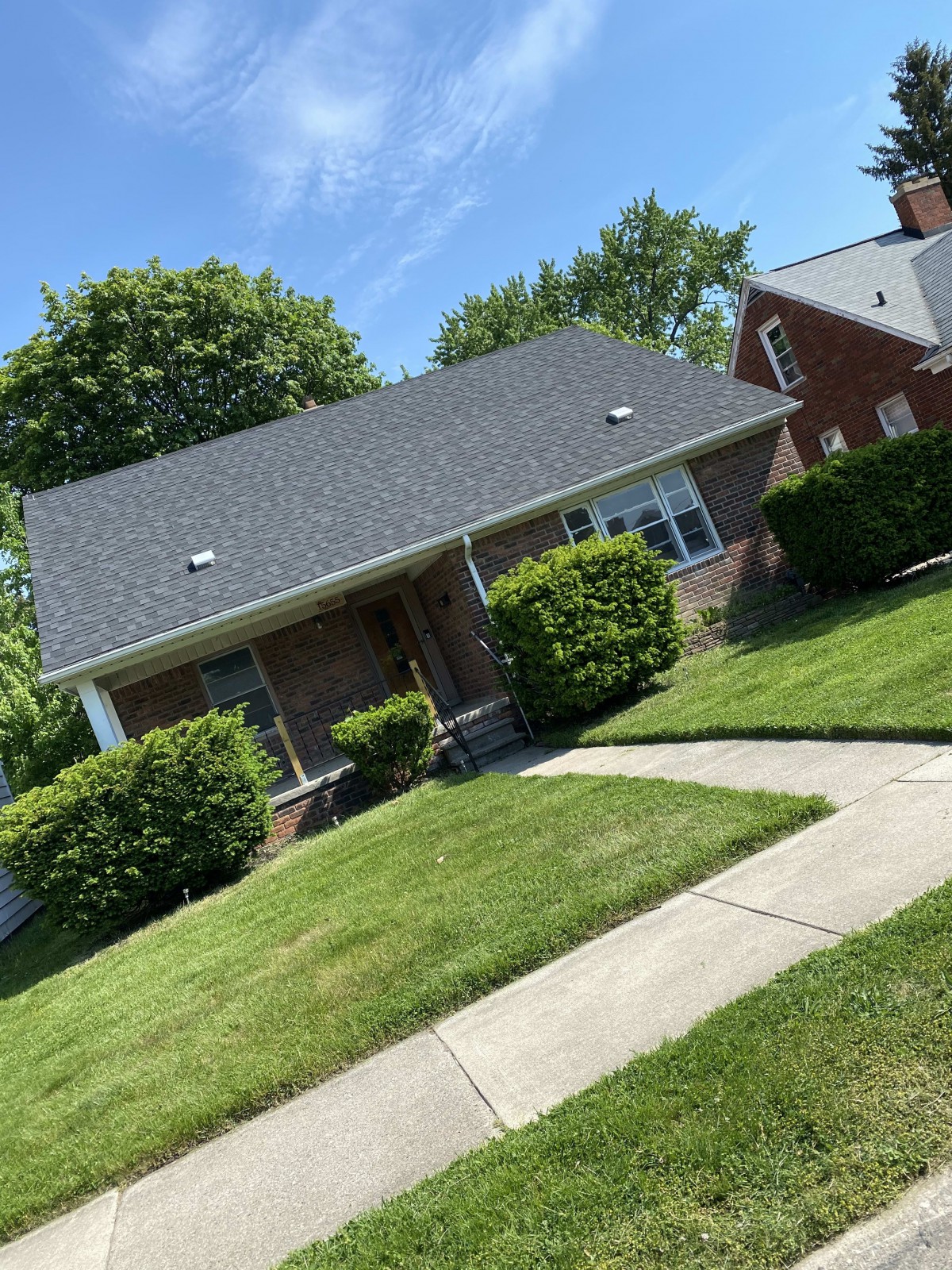 A suburban house with a well-maintained lawn and surrounding greenery.