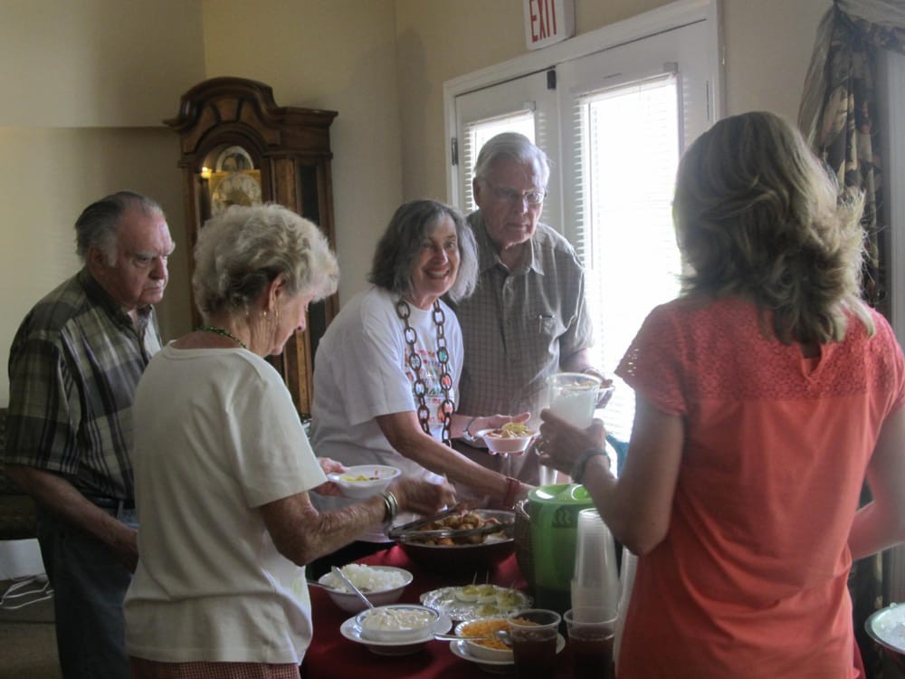 A group of people socializing around a table with food.