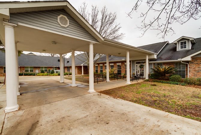 A residential building with a covered driveway supported by white columns.