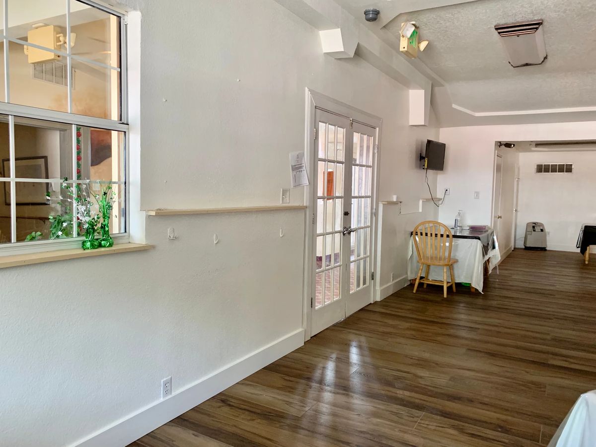 A bright and airy interior with wooden flooring, featuring a dining area next to French doors and decorative plants.