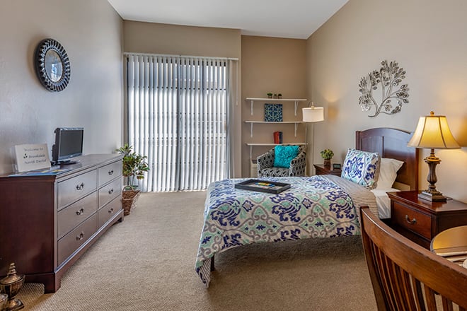A cozy bedroom with a single bed, wooden furniture, and soft lighting.