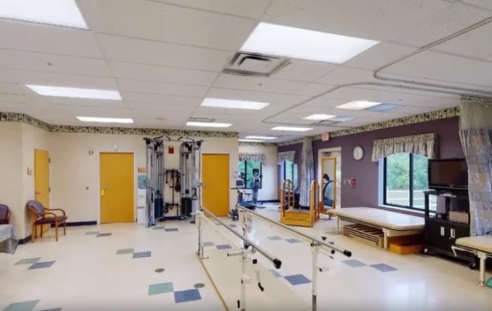 A physical therapy room equipped with parallel bars and various exercise machines.