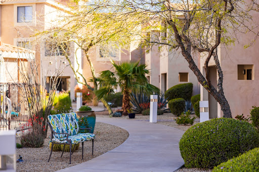 A serene courtyard walkway featuring vibrant outdoor seating and lush greenery.